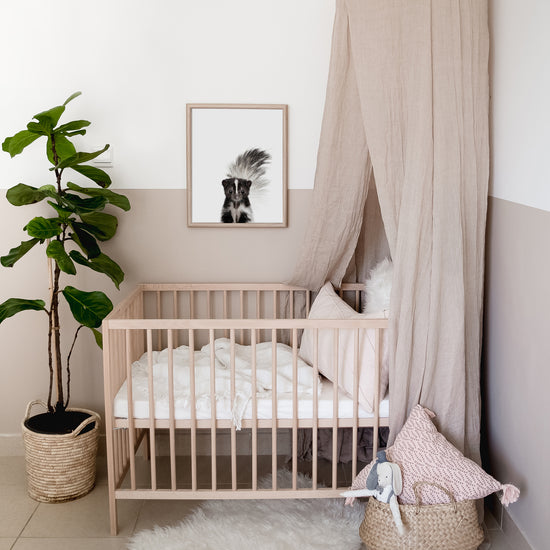 Baby Skunk print framed above a crib in a woodland nursery 